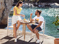 Un homme et une femme en baskets blancs sont assis à une table au bord de l'eau.