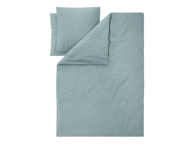 Parure de lit bleu clair avec housse de couette et taies d'oreiller texturées.