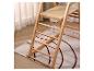 Échelle en bois avec étagère, sur un tapis à motif géométrique et des rideaux clairs.