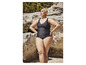 Une femme porte un maillot de bain noir sur la plage.