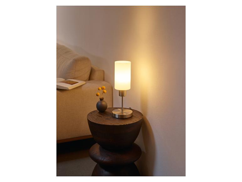 Lampe de table moderne avec abat-jour blanc laiteux sur une table en bois.
