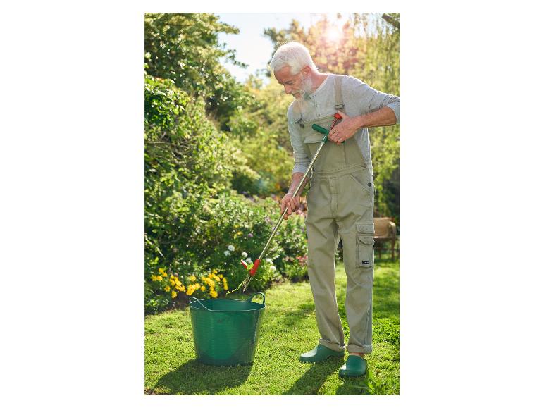 Un homme utilise une pince à mauvaises herbes pour retirer les mauvaises herbes de son jardin.