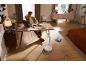 Un aspirateur robot blanc nettoie le sol d'un salon moderne avec un homme au bureau.