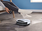 Une personne utilise une télécommande pour contrôler un aspirateur robot.