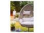 Chaise suspendue avec coussins et un homme descendant des escaliers dans un jardin.