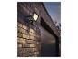 Projecteur LED avec détecteur de mouvement sur un mur de briques au-dessus d'une porte de garage.