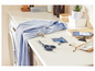 Une chemise bleue, des ciseaux et du fil sont posés sur une table, prêts à être cousus.