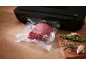 Machine sous vide noire avec un morceau de viande emballé sous vide et des herbes.