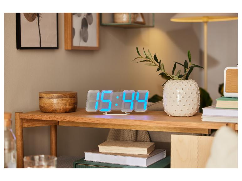 Horloge LED digitale, livres et vase décoratif sur meuble en bois.