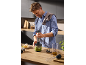 Un homme utilise un mixeur plongeant pour préparer du pesto dans la cuisine
