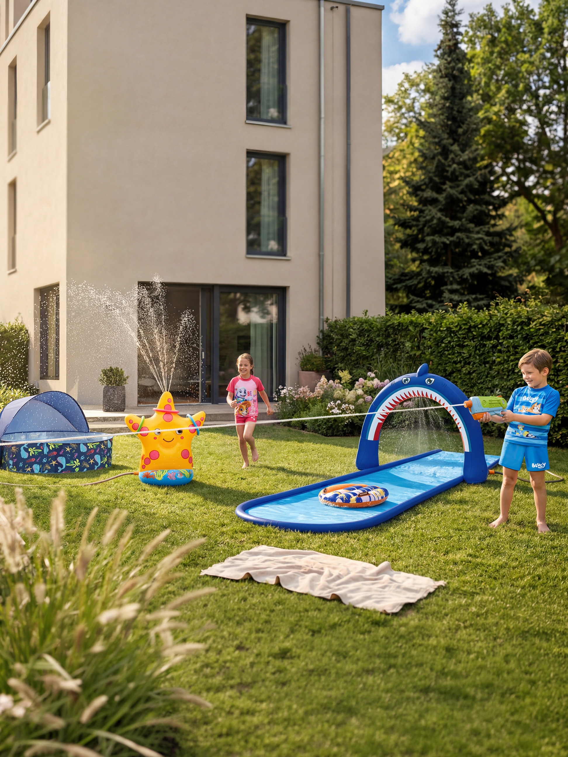 Enfants jouant avec un arroseur de jardin étoile de mer et un toboggan aquatique requin.