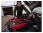 Un homme utilise un chargeur de batterie Ultimate Speed ​​sur une voiture.
