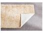 Tapis beige en fausse fourrure avec sous-couche antidérapante.