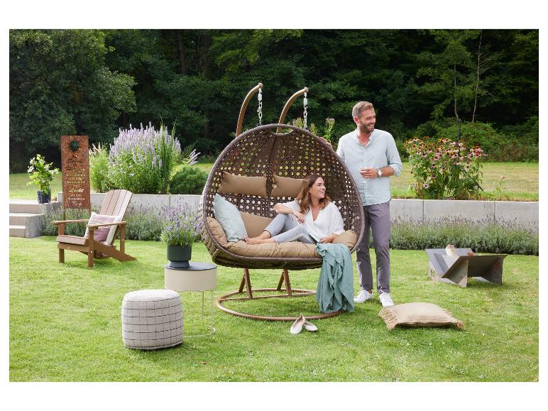 Couple dans un fauteuil suspendu dans le jardin avec mobilier et plantes.