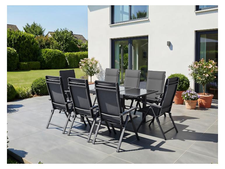 Ensemble de salle à manger d'extérieur gris sur une terrasse ensoleillée avec une maison et un jardin.