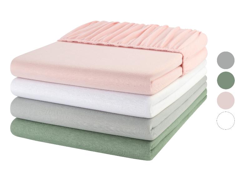Une pile de draps roses, blancs, gris et verts.