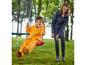 Un enfant dans une combinaison de pluie orange se balance sur une balançoire, un adulte le regarde.
