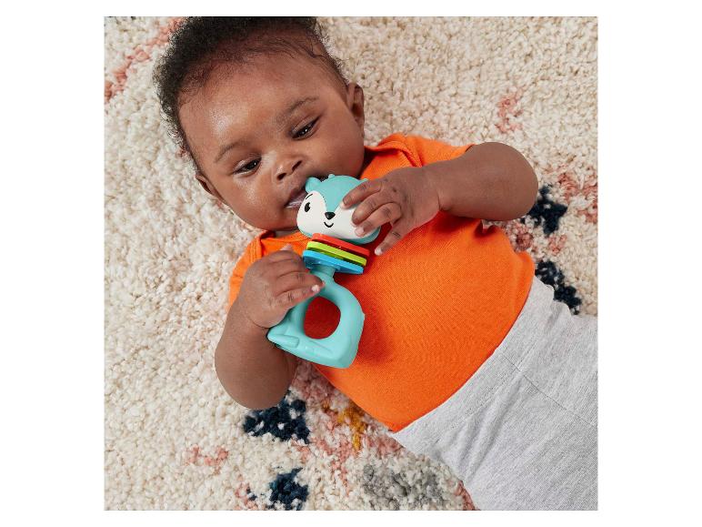 Bébé allongé sur un tapis, jouant avec un hochet en forme de renard bleu.