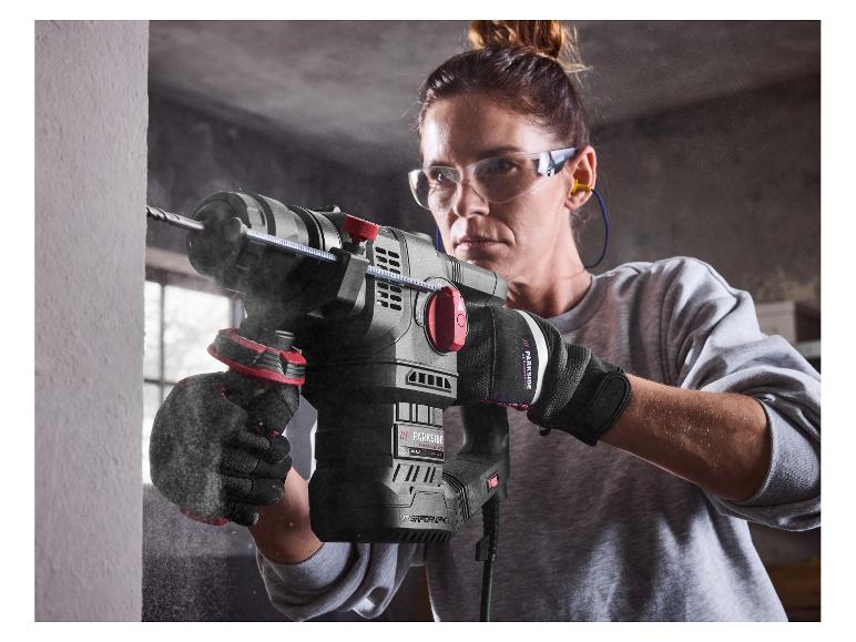 Femme en équipement de sécurité utilisant un marteau perforateur Parkside Performance sur un mur.
