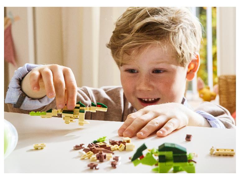 Un enfant souriant joue avec des jouets de construction en forme de dinosaures.