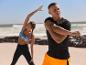 Deux personnes en vêtements de sport font des étirements sur la plage.