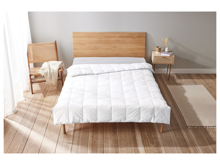 Une couette blanche sur un cadre de lit en bois dans une chambre à coucher.
