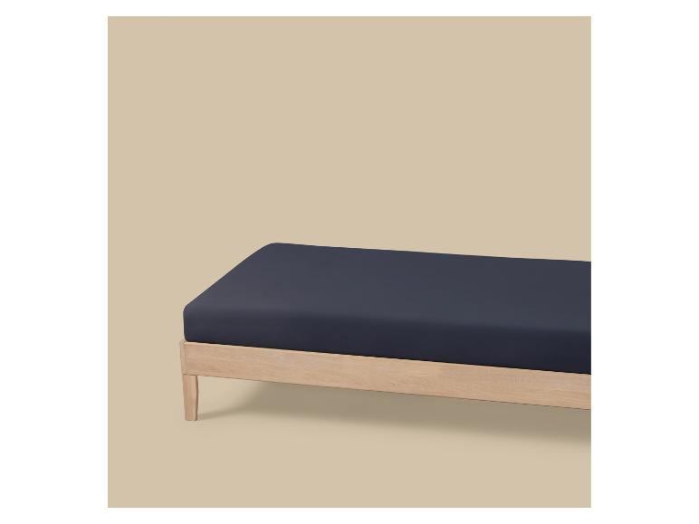 Drap-housse bleu foncé sur un cadre de lit en bois clair.