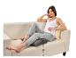 Une femme assise sur un canapé avec un coussin chauffant Beurer.