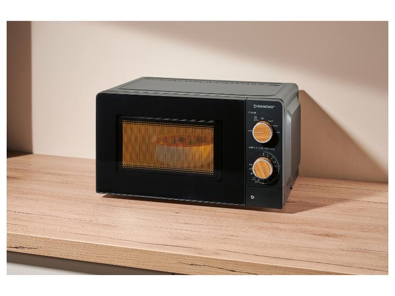 Four à micro-ondes noir avec boutons en bois sur un comptoir en bois.