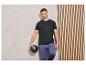 Un homme en t-shirt noir et pantalon bleu, tenant un ballon noir.