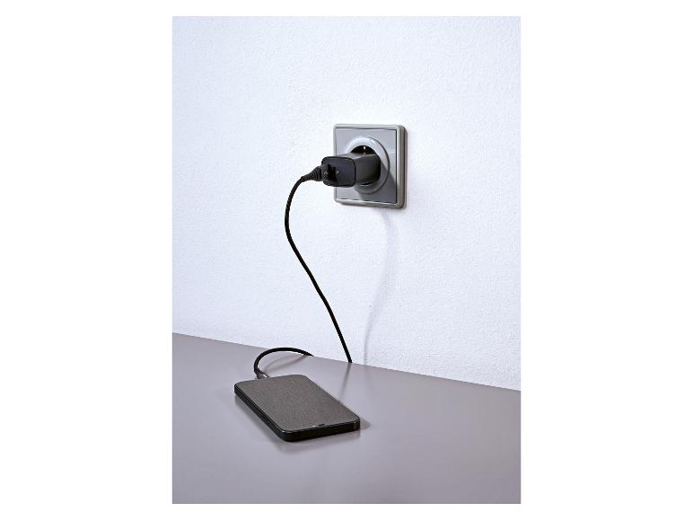 Smartphone en charge depuis une prise murale avec un chargeur et un câble noirs.