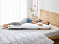 Une femme allongée sur un lit avec un oreiller et une couverture.
