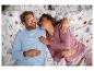Un couple au lit avec des draps fleuris.