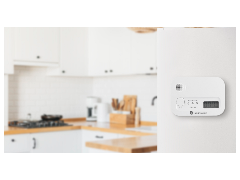 Détecteur de gaz blanc avec affichage numérique et bouton de test, monté sur un mur blanc dans une cuisine moderne.