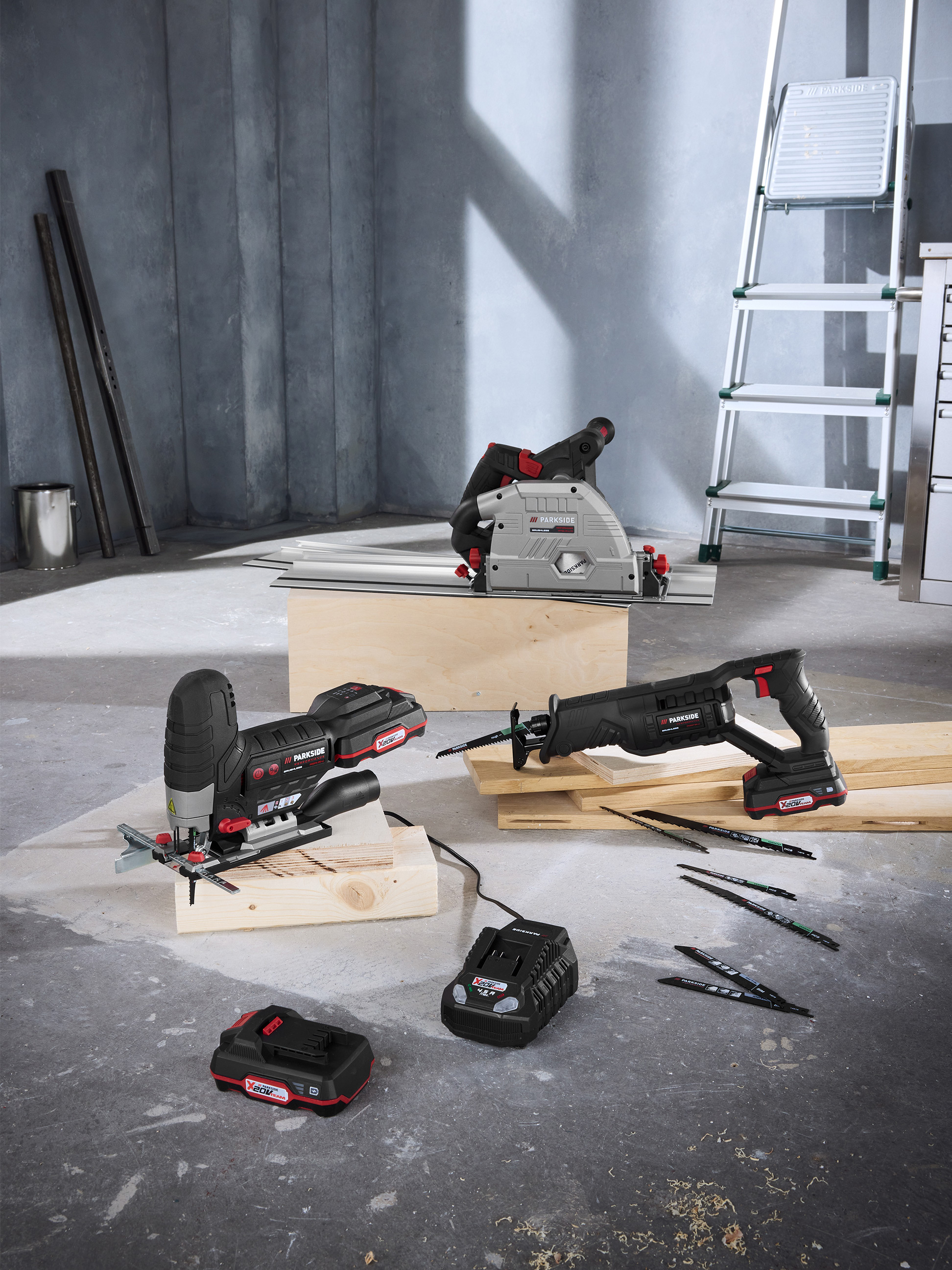 Outils électriques Parkside : scie plongeante, scie sauteuse et scie sabre avec batteries et accessoires en atelier.