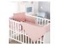 Lit bébé blanc avec parure de lit rose, oreiller et tour de lit dans une chambre de bébé.