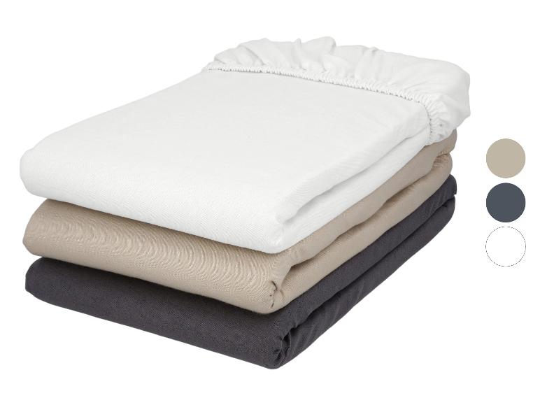 Piles de draps-housses en blanc, beige et gris foncé avec des échantillons de couleur.