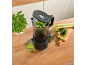 Extracteur de jus noir sur un comptoir en bois, préparant du jus vert de concombres et céleri.