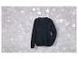 Un pull bleu foncé à câble, suspendu à un cintre avec des étoiles scintillantes.