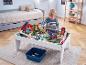 Garçon jouant avec une table de train en bois avec ponts et bâtiments dans une chambre d'enfant.