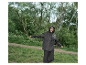 Femme en imperméable et pantalon foncés profitant de la pluie dans un parc.