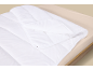 Couette blanche avec boutons-pression sur un lit avec un drap beige clair.
