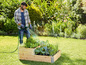 Un homme arrose un jardin potager avec un tuyau d'arrosage Gardena.