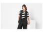 Femme en blazer noir sans manches, t-shirt rayé et pantalon noir.