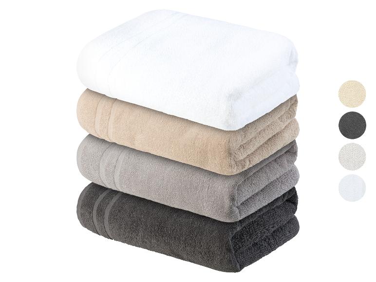 Une pile de serviettes de toilette en blanc, beige, gris et gris foncé.