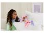 Un enfant joue sur le lit avec une poupée Barbie et un snowboard.