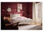 Une chambre à coucher avec une parure de lit à motif floral sur un lit, complétée par un tapis beige minimaliste et des murs rouge foncé.
