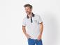 Un homme porte un polo blanc à thème marin et un jean bleu.