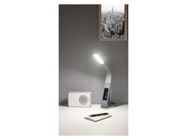 Une lampe de bureau avec une horloge intégrée et une radio sur un bureau.