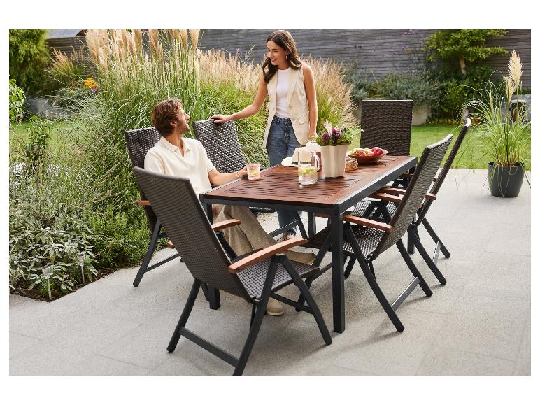 Couple dînant en plein air à une table de jardin en bois avec des chaises en osier.